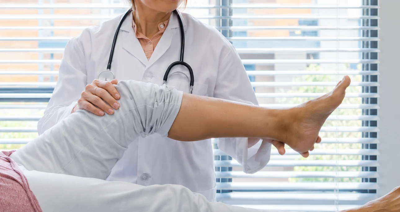 Clinician examining a patient's leg in an orthopaedic consultation